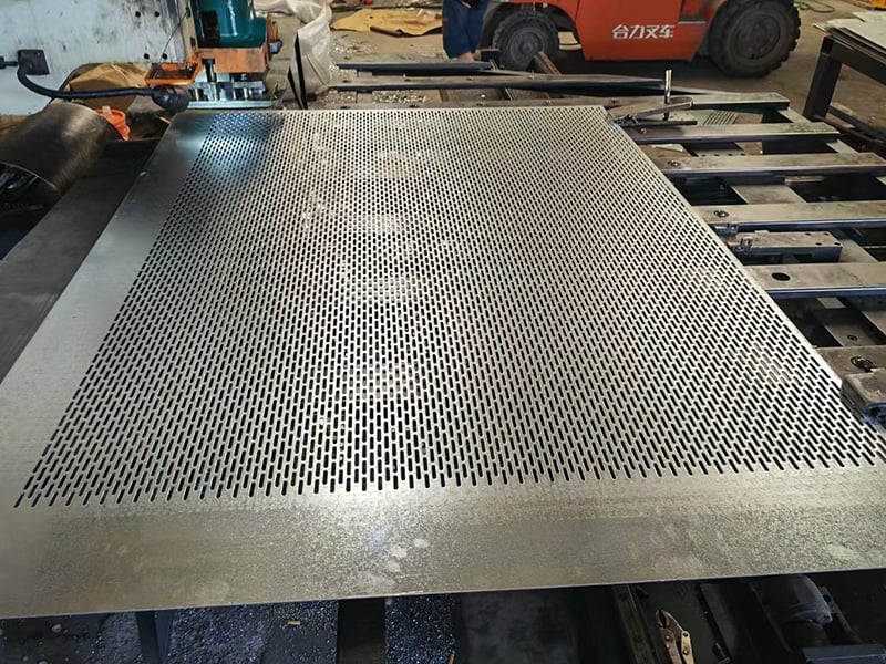 Large slotted perforated metal sheet on a fabrication table