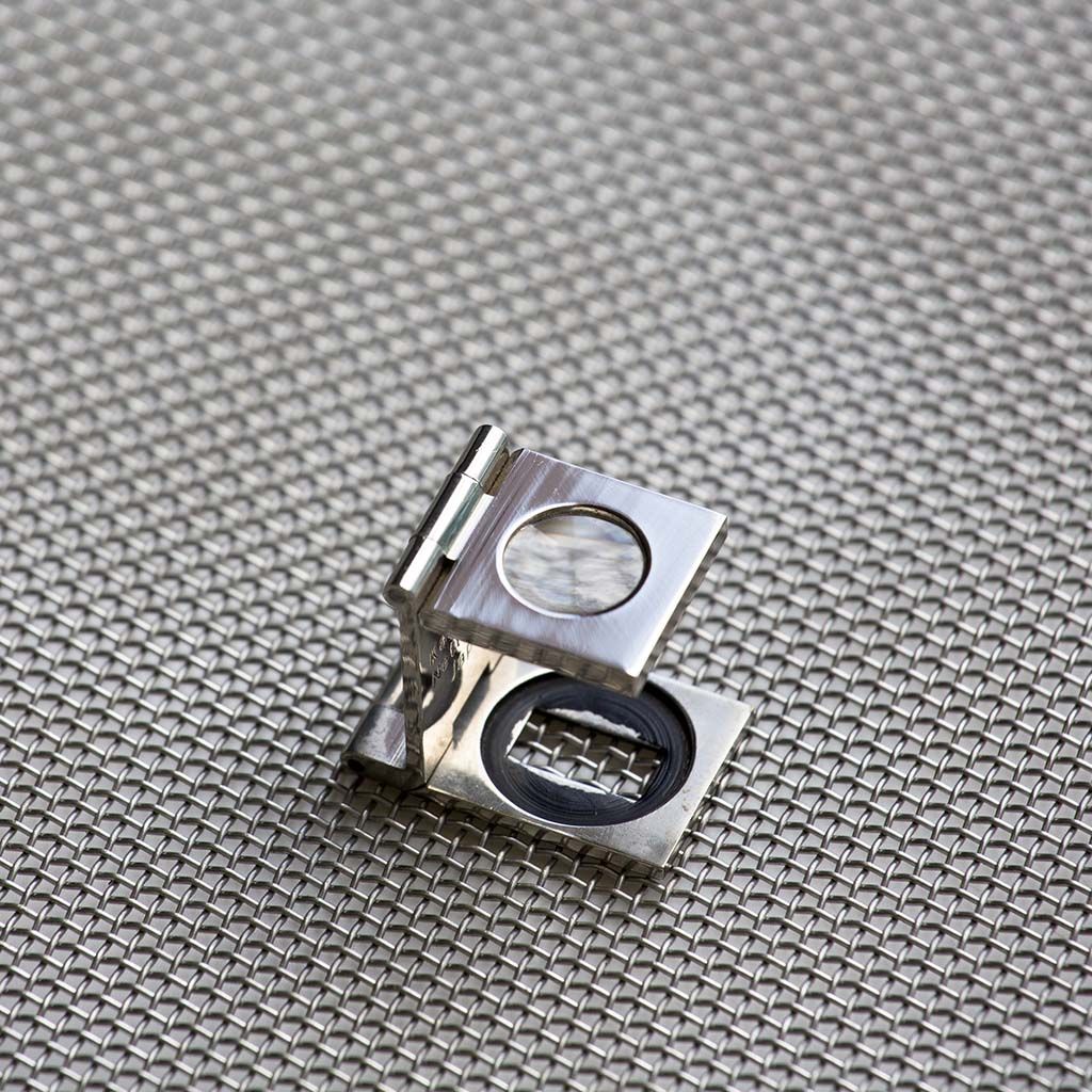 Magnifier positioned over a woven stainless steel mesh aperture